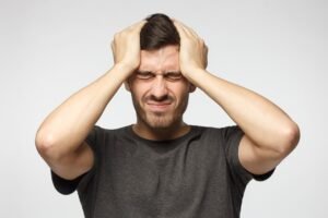 Ein Mann mit Kopfschmerzen, der elend und erschöpft aussieht.